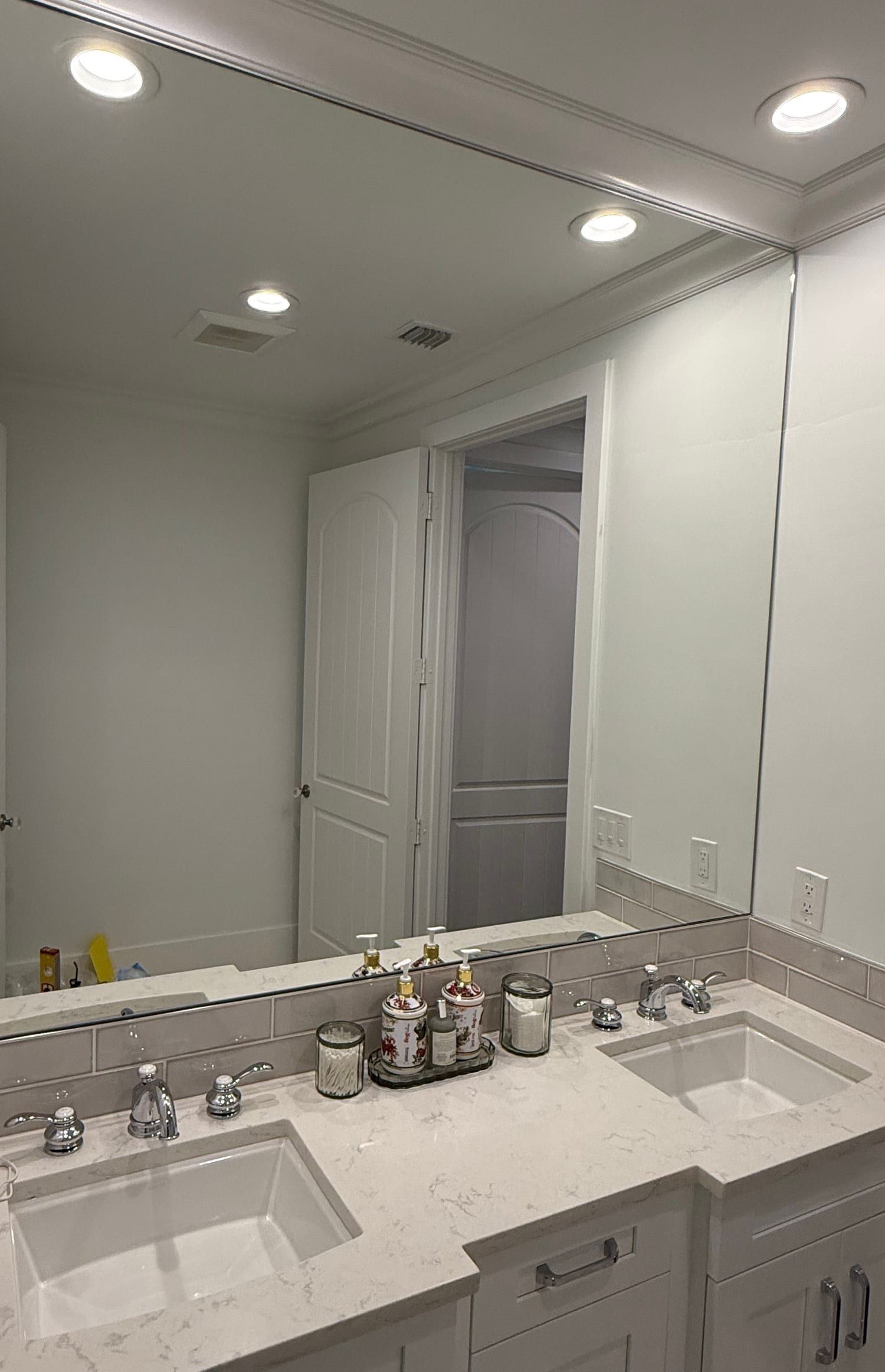 Large frameless mirror with polished edges running the full width of a double vanity and returning around the corner of the wall